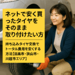日本人の整備士が明るい整備工場で笑顔でタイヤ交換をしている様子。ネットで購入したタイヤを持ち込みで交換する、親しみやすく安心できる雰囲気を表現したリアルな写真。